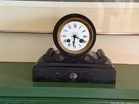 Front view of black slate French mantel clock on shelf