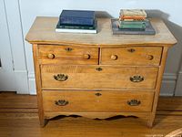Front view showing two small upper drawers, two large lower drawers, hardware and scalloped base