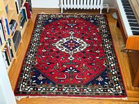 Full view of red Indian wool rug on floor