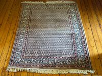 Full view of rectangular wool rug showing overall pattern and fringe