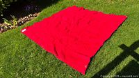 Full view of red wool blanket spread on grass