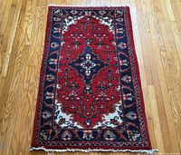 Full view of the red and navy hand-knotted rug