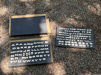 Three cardboard trays on gravel containing assorted white plastic reader-board characters
