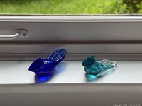 Cobalt and aqua glass bluebird figurines on windowsill