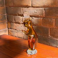 Full view of amber glass rabbit on wood surface, shows overall form and color
