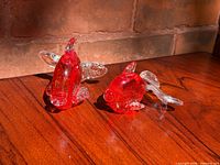 Pair of red and gold aventurine Murano glass fish on wood surface