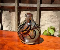 Front view of rounded amber art glass vase with black swirl and aventurine shimmer