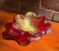 Full view of red Murano glass bowl showing ruffled form and color