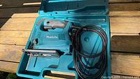 Jigsaw inside molded carry case showing tool, cord, blade and interior form