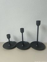 Front view of three black metal candlesticks in graduated heights
