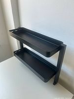 Full view of two-tier black metal shelf on desk