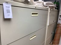 Close view of the two beige metal four-drawer lateral file cabinets with MaxSold tag visible