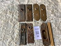 All seven brass backplates laid out with ruler for scale