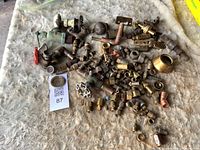 Tabletop view of entire assortment of brass, copper and steel plumbing fittings scattered on surface