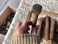 Hand holding one bolt to show overall size and head form