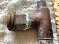Close-up of brass male-threaded valve/fitting attached to copper T-pipe