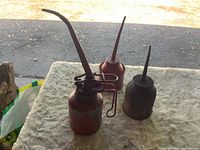 Three oil cans on surface showing relative sizes and spouts