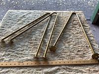 Three gold hairpin legs laid flat with ruler for scale