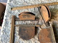 Four window sash pulleys beside rulers showing size and mounting plates