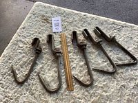 All five hooks laid flat beside 12-in. ruler for scale