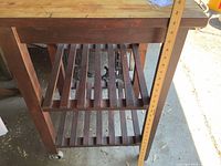 Side view showing butcher block top, frame color, two slatted shelves and ruler indicating height