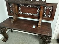 Full view of bench showing carved back panel and legs