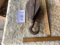 Pulley laid flat with ruler for scale showing rusted surface