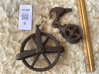 Overall lot showing both cast-iron pulley wheel and block with hook alongside rulers for scale