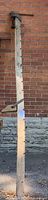 Full length view of wooden sash clamp leaning against brick wall