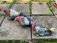 All three reclining gnome figurines on patio stones