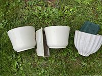 Four cream ceramic pots laid on grass