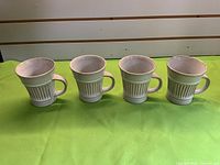 Four cream Dansk Flamestone mugs side by side showing overall design and condition