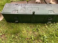 Top view of closed green metal box showing stamped panel and lid hardware