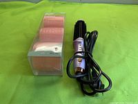 Curling iron brush and packaged pink rollers on green background