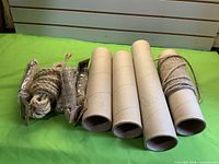 Four cardboard tubes with various jute rope coils on green backdrop