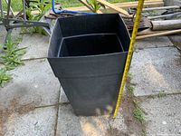 full view of tall black square plastic planter with tape measure showing 24 in height
