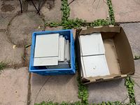 Two containers holding stack of beige square tiles