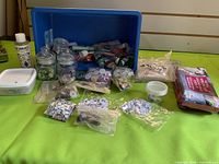 Group shot of all craft supplies laid out including eyes, noses, jars, paint, clay and blue tote