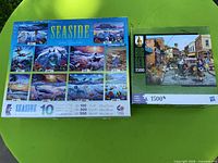Front of both puzzle boxes showing Seaside multi-puzzle set and Big Ben 1500-piece puzzle