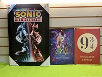 Group shot of all three wall art pieces: Sonic print, Beetlejuice metal sign, Hogwarts Express metal sign
