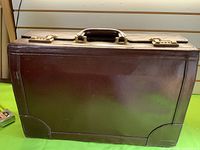 Front view of brown leather suitcase closed showing smooth exterior