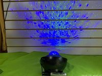 Galaxy light projector on green surface, projecting blue star pattern