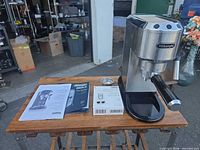 Front view of espresso machine with portafilter, manuals and descaler on table
