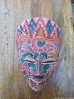 Frontal view of carved wooden mask showing full painted design