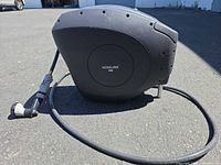 Hoselink retractable hose reel with hose and nozzle on pavement