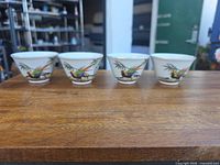 Front view of the four matching tea cups on wooden surface