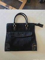 Front view of Louis Feraud black canvas tote showing overall design, double handles, front flap pocket, leather trim