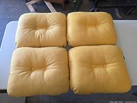 Top view of four matching yellow seat cushions