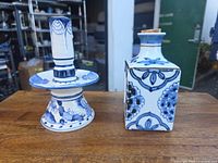 Full view of candlestick and bottle showing forms and matching Delft-style decoration