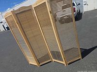 Full view of four-panel wood room divider standing partially folded